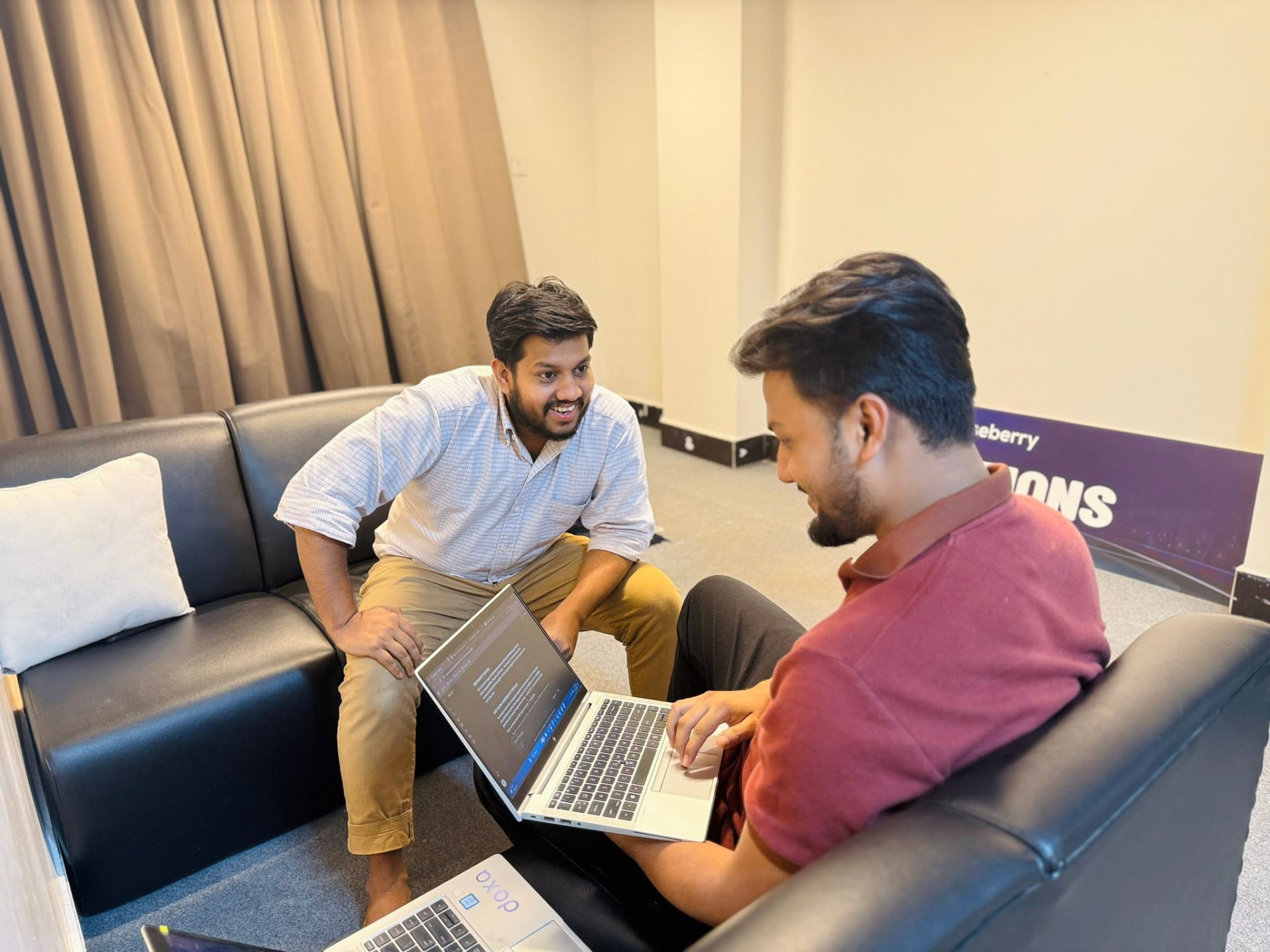 Two Gooseberry team members collaborating on a laptop in the office lounge